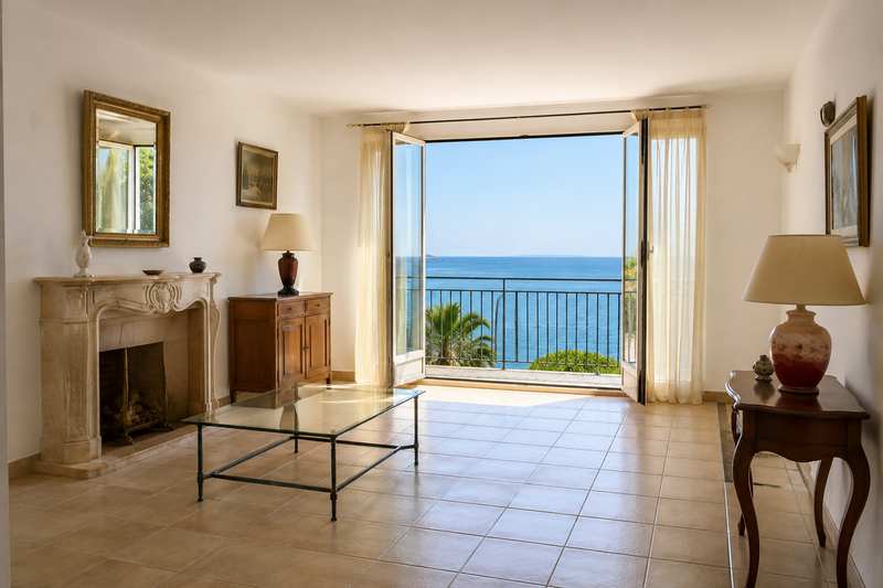 Séjour d'appartement niçois à moitié vide devant une baie vitrée