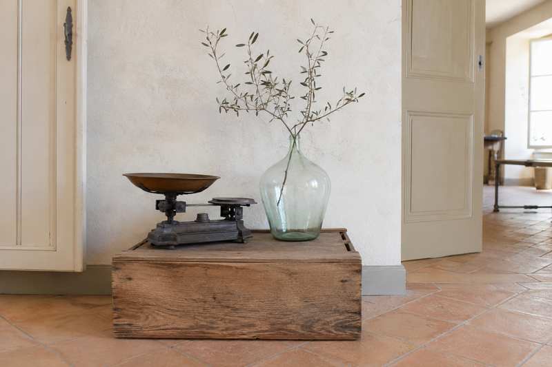 Vase en verre soufflé et balance ancienne posés sur une caisse retournée