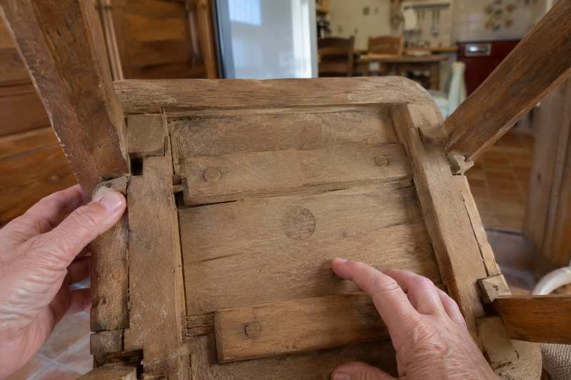 Dessous d'une chaise retournée montrant un assemblage à tenon et une estampille