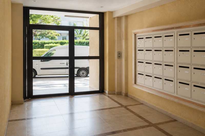 Hall d'immeuble et boîtes aux lettres vus depuis la vitre d'un fourgon à l'arrêt