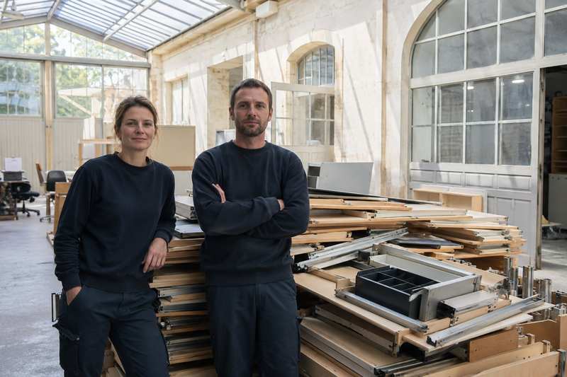 Mobilier démonté et rangé par lots dans un atelier vitré avant reconditionnement