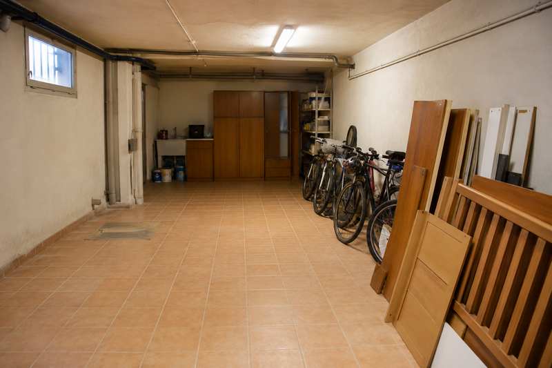 Sous-sol de pavillon eclaire au neon, velos et meubles demontes ranges le long du mur
